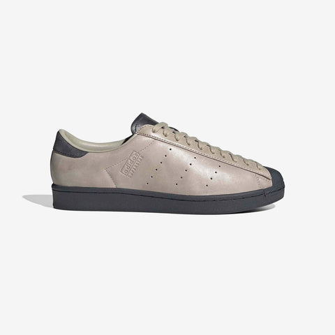 Beige leather low-top sneaker with a dark grey rubber toe cap, heel counter, and sole, shown in profile on a white background.