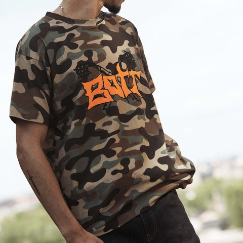 Person wearing a short-sleeved camouflage t-shirt with a large orange graffiti-style BOTT logo across the chest.