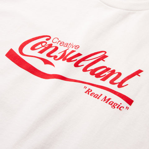 Close-up of a white t-shirt with red script text reading "Creative Consultant" and "Real Magic" in quotes below.