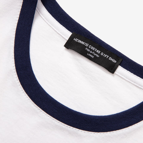 Close-up of a white crew-neck t-shirt with navy ringer trim at the collar, showing a black woven label reading "(CONNI3) COST45 GIFT SHOP", "Phoebe-Porter", and "LARGE".