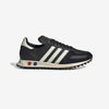 Black low-top sneaker with three cream stripes on the side, cream midsole, and rubber lugged outsole with red and blue accent dots.