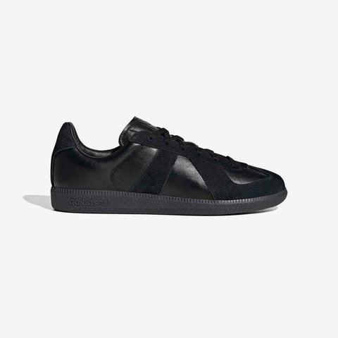 Black low-top sneaker in black leather and suede with a black rubber sole, shown from the side on a white background.