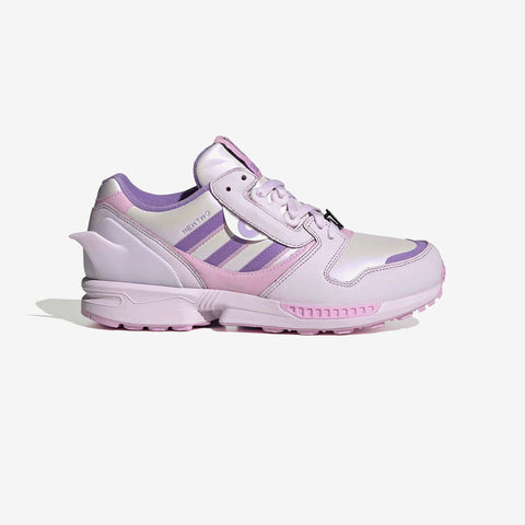 Pink and lilac low-top sneaker with purple stripes, a silver tongue tag, and a chunky pink rubber sole, shown from the side.