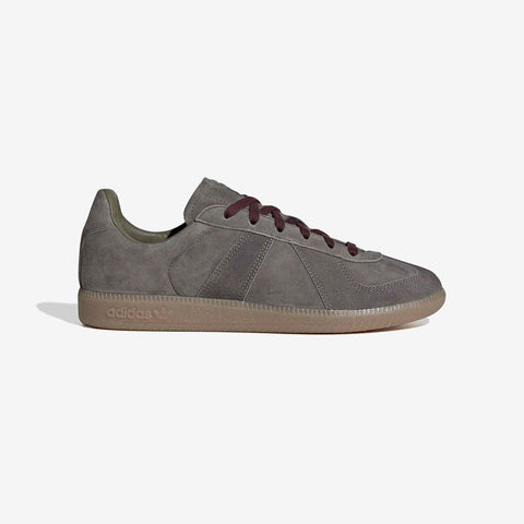 Grey suede low-top sneaker with dark burgundy laces, olive heel tab, and a gum rubber sole with embossed adidas branding.