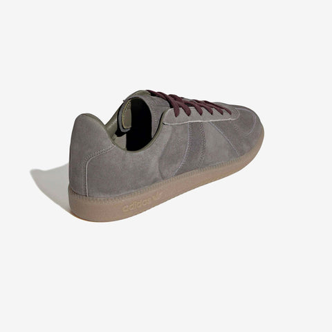 Grey suede low-top sneaker with burgundy laces and a gum rubber sole, shown from the rear three-quarter angle on a white background.