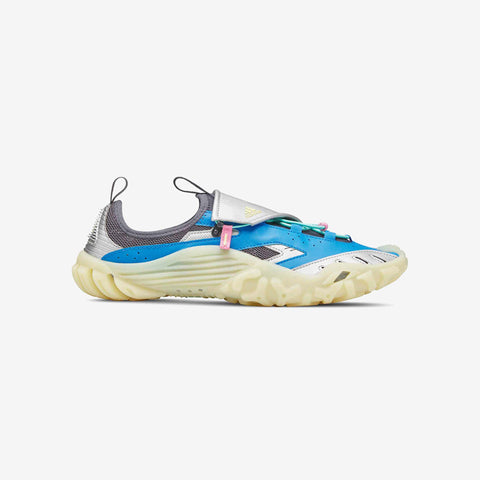 Side view of a blue, silver, and pale yellow chunky athletic sneaker with a thick cushioned sole, a strap across the midfoot, and a pull tab at the heel.