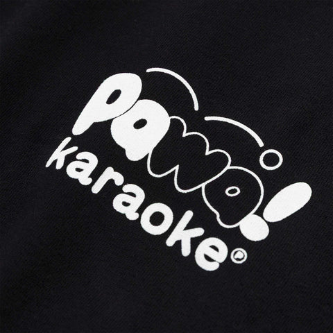 White printed logo reading "Pawa karaoke" with stylised bubble lettering on a black fabric background.