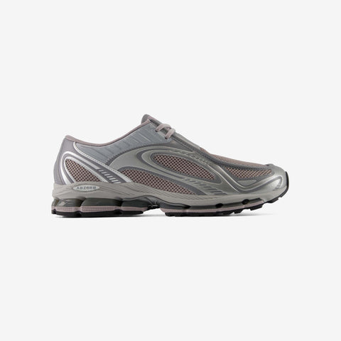 Grey and mauve running shoe in side profile, with mesh panels, silver overlays, and a chunky sole with visible cushioning pods.