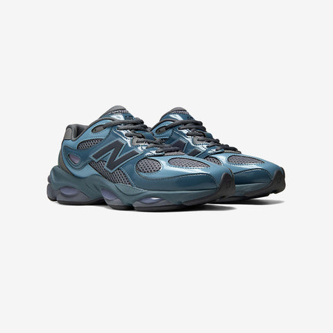 Pair of blue-grey chunky running sneakers with mesh and glossy panels, a black N logo on the side, and purple-tinted cushioned soles.