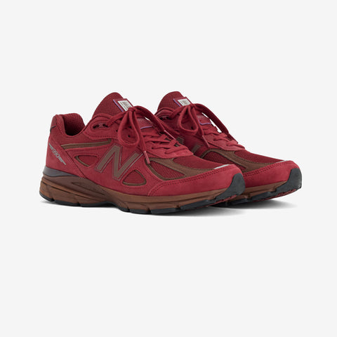 Pair of red running sneakers with brown suede overlays, a brown N logo on the side, and a brown and black sole.