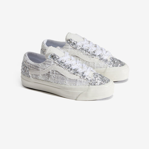 Pair of low-top sneakers with silver sequin and textured tweed-like white uppers, white laces, and a cream rubber sole.