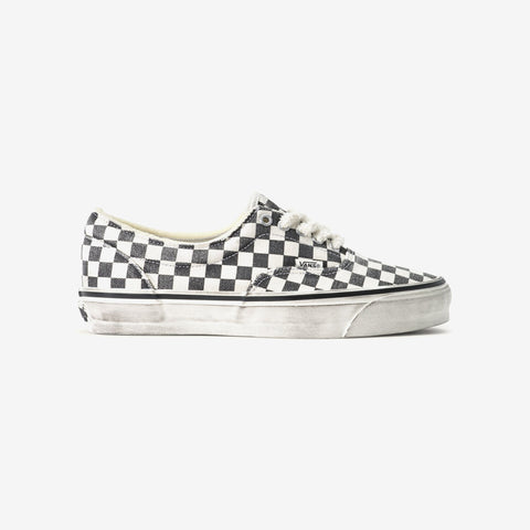 Black and white checkerboard low-top sneaker with white laces and a distressed, worn-look white sole, shown from the side on a plain background.