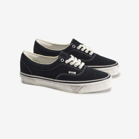 Pair of black low-top canvas sneakers with white laces and worn white rubber soles, shown from the side angle.